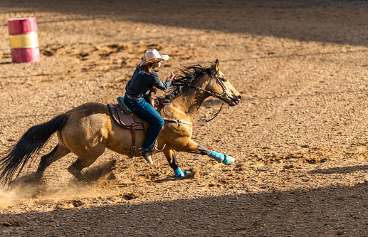 Young cowgirl barrel racing at a local rodeo arena