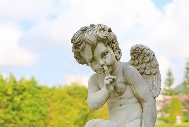 Photo of Cupid sculpture in summer garden outdoor.