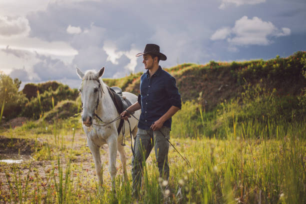istock Man walking around a lake with his white horse 1162676096