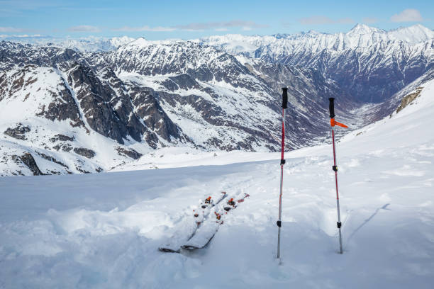 Skis and poles set up near the top of a mountain overlooking backcountry skiing area near Hatcher Pass, Alaska. After a long hike, skis and poles sit near the top, overlooking a vast glacial valley below Snowbird Glacier in the Hatcher Pass area of the Talkeetna Mountains, Alaska. talkeetna mountains stock pictures, royalty-free photos & images