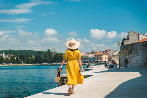 mujer caminando por el muelle del mar en el día de verano en el vestido de sol amarillo photo