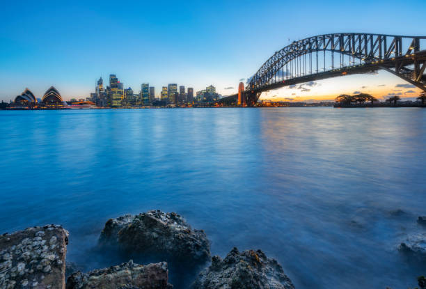 сумерки вид на гавань сиднея и сидней гавани мост против неба, австралия - the rocks sydney harbor sydney australia new south wales стоковые фото и изображения