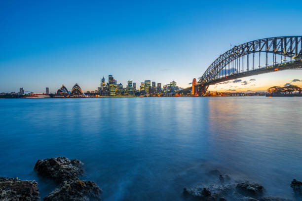 сумерки вид на гавань сиднея и сидней гавани мост против неба, австралия - the rocks sydney harbor sydney australia new south wales стоковые фото и изображения