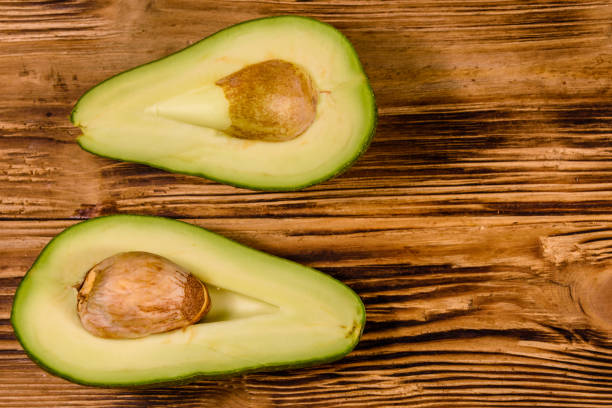 istock Halved avocado fruit on a wooden table. Top view 1162695590