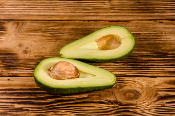 istock Halved avocado fruit on a wooden table 1162695592