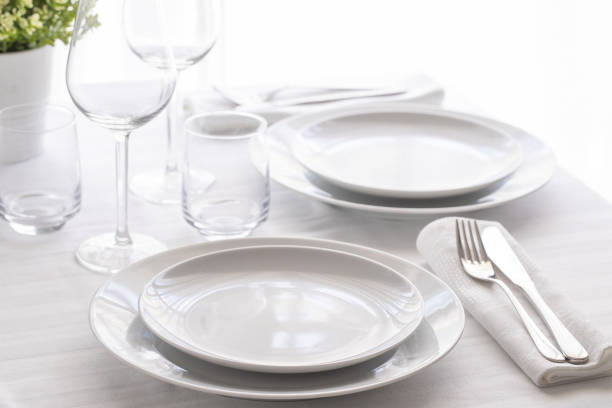 istock Table setting white and grey colour. Empty glasses and plates set with napkin and cutlery. Restaurant interior background. 1162698579