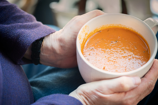 Personal perspective of a woman eating a vegan meal of tomato soup.   Vancouver, British Columbia, Canada.