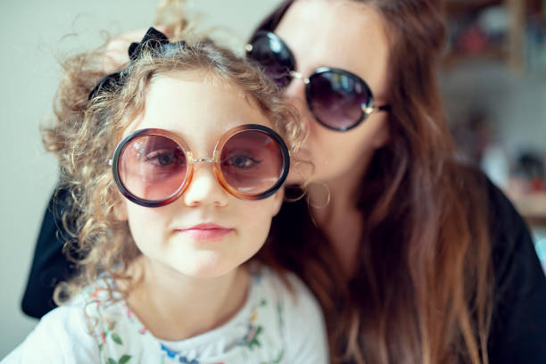 Germany, Happy mother and daughter with big sunglasses look into the camera.