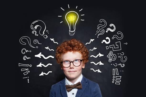 istock Small boy in glasses and lightbulb on blackboard background in classroom 1162709236