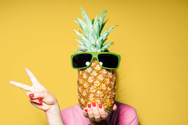 istock Woman and pineapple on her head standing over color background 1162709299