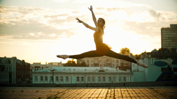 istock Young woman ballerina jump performing a split - bright sunset 1162709987