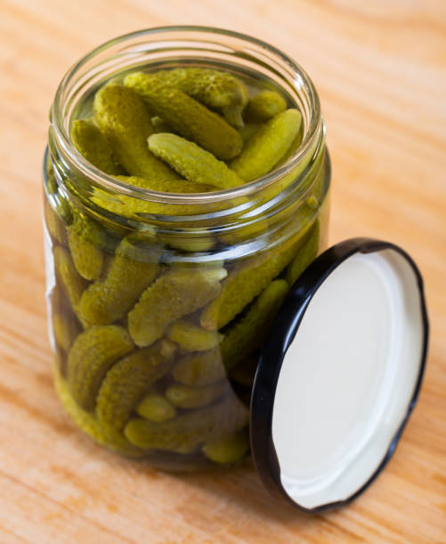 istock Opened  glass jar with pickled cucumbers on wooden background 1162711278