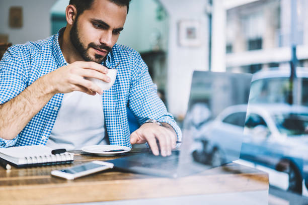 istock Pensive man reading news from networks browsing website on netbook drinking coffee on break,skilled male freelancer watching video online on laptop computer working remotely in cafe interior 1162713037