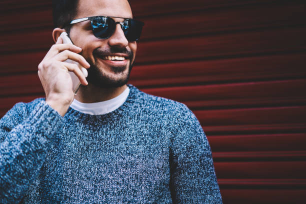 istock Cheerful trendy dressed guy talking on mobile phone standing outdoors,handsome man in sunglasses having telephone conversation in roaming satisfied with connection spending time on urban settings 1162713043