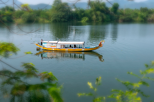 Hue, Vietnam - April 9th, 2019: Cruise lonely boat at Perfume river. This is eco-tourism means peaceful waterways in the imperial city in Hue, Vietnam