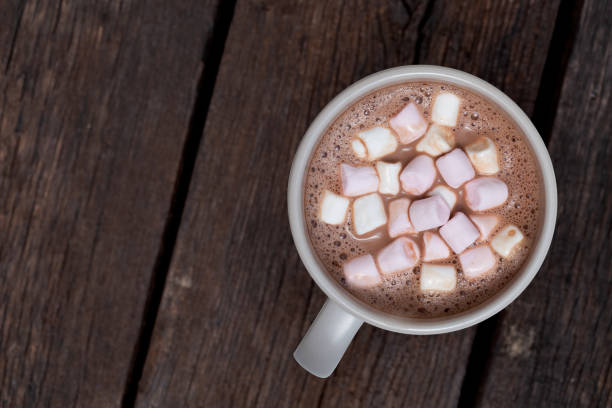 Hot chocolate with small marshmallows in a grey ceramic mug isolated on dark brown wood from above. Space for text.