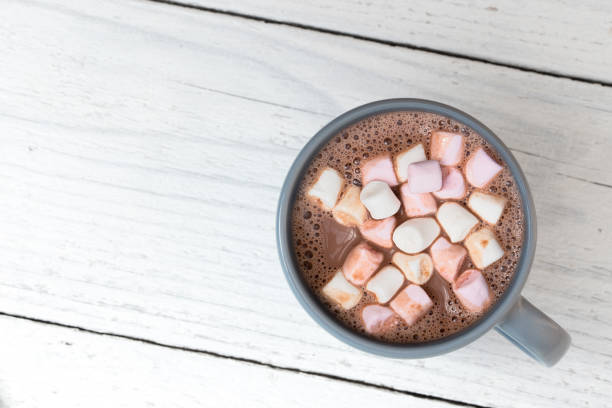 istock Hot chocolate with small marshmallows in a blue-grey ceramic mug isolated on white painted wood from above. Space for text. 1162716551