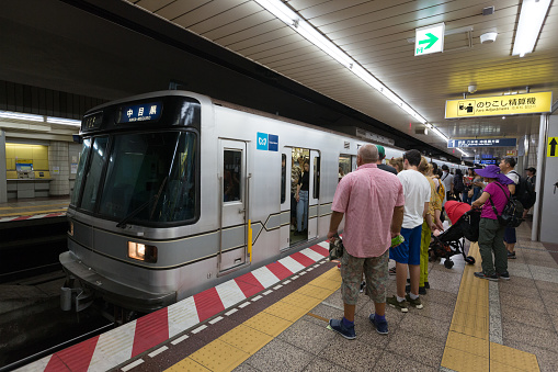 Tokyo, Japan - August 16, 2018: Passengers at the Tsukiji Station in Tsukiji, Chuo, Tokyo, Japan. This train is operated by Tokyo Metro on the Hibiya Line.