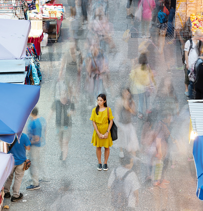 Woman using phone, motioned blurred market