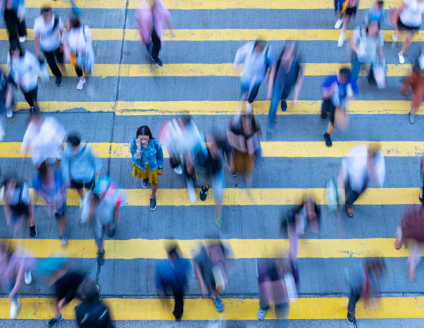 istock Young woman standing out, with phone, in motion blurred crowd 1162717949