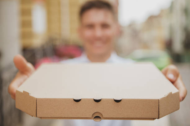 istock Handsome man walking in the city carrying pizza box 1162718554