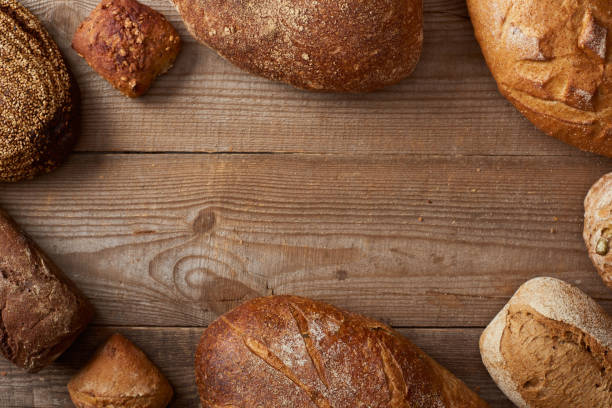 top view of homemade loaves of bread and buns on wooden rustic table with copy space