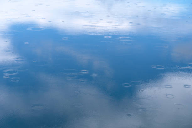 light blue reflection sky and cloud on the texture of water with ripples from raindrop nature background