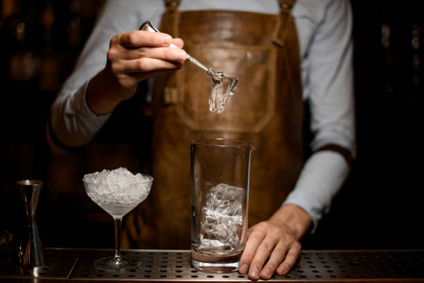 istock Male bartender putting an ice cube to the measuring glass cup 1162725286