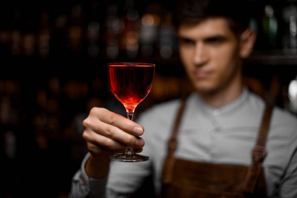 Male bartender serving a red alcoholic cocktail in the glass