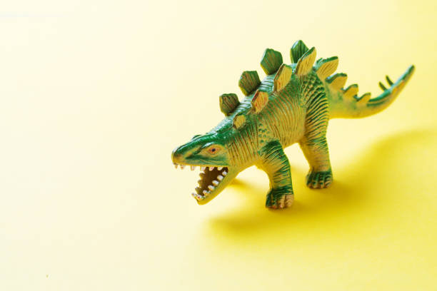 istock Dinosaur on a yellow background. Plastic rubber toy. Selective focus. 1162726062