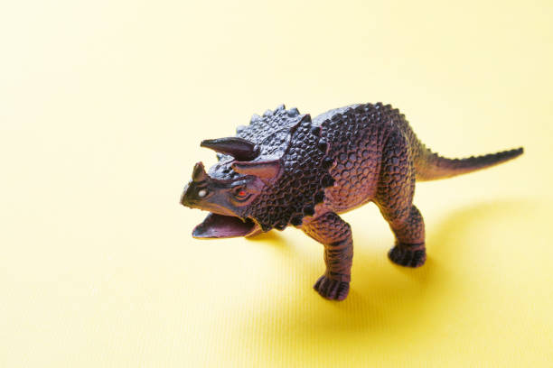 istock Dinosaur on a yellow background. Plastic rubber toy. Selective focus. 1162726087