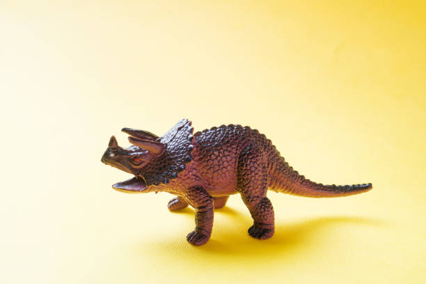 istock Dinosaur on a yellow background. Plastic rubber toy. Selective focus. 1162726130