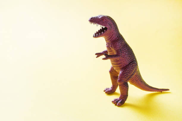 istock Dinosaur on a yellow background. Plastic rubber toy. Selective focus. 1162726177