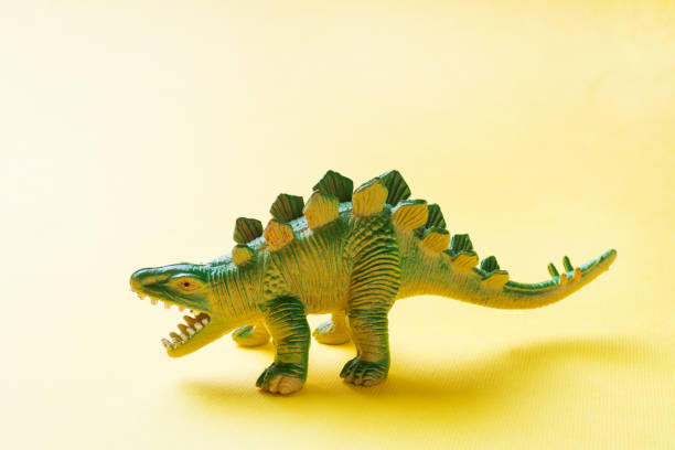 istock Dinosaur on a yellow background. Plastic rubber toy. Selective focus. 1162726190