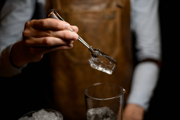 istock Professional bartender putting a big ice cube to the measuring glass cup 1162726249