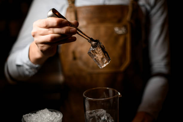 istock Professional male bartender putting a big ice cube to the measuring glass cup 1162727401