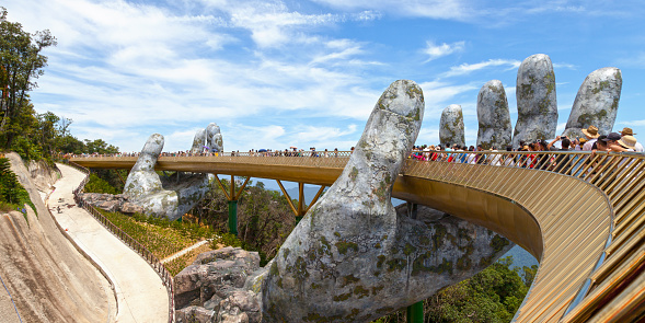 Bà Nà Hills, Vietnam - August 22 2018: Tourists walking on the Golden Bridge, a 150 m long pedestrian bridge in the Bà Nà Hills, near Da Nang, Vietnam. The Bà Nà Hills are located in the Truong Son Mountains, which are part of the Annamite Range.