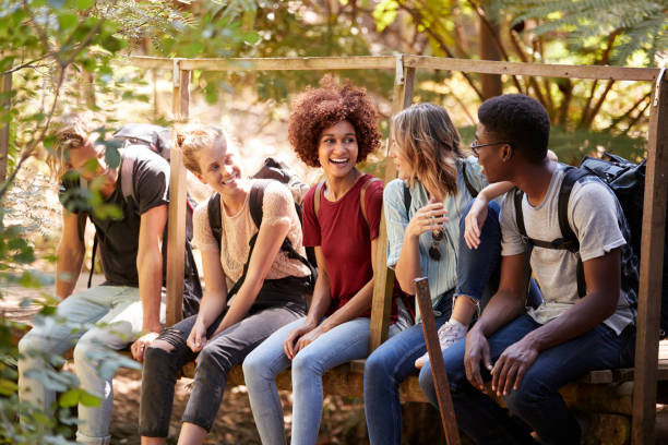 istock Five millennial friends sitting on a bridge in a forest talking during a hike, three quarter length 1162736627