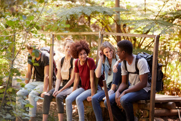 istock Five millennial friends sitting on a bridge in a forest talking during a hike, three quarter length 1162737865