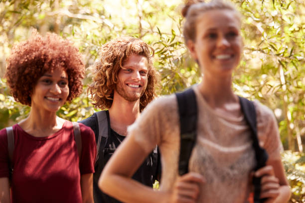 istock Three happy millennial friends wearing rucksacks on a hike in a forest, close up 1162737866
