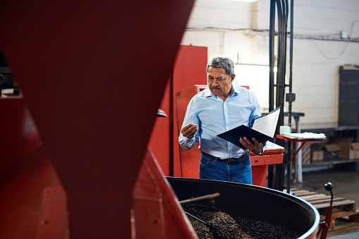 Shot of a mature man overseeing the production process in a coffee distribution warehouse