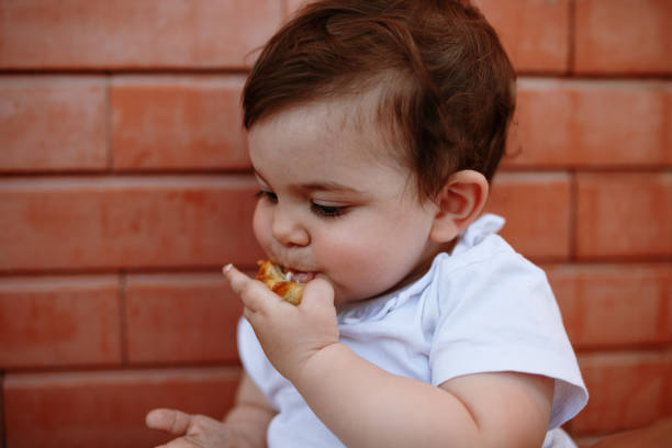 istock Cute Boy Eating Food Against Wall 1162738614