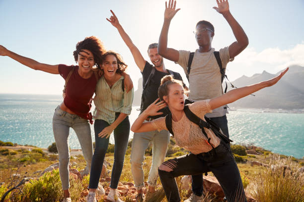 Millennial friends on a hiking trip celebrate reaching the summit and have fun posing for photos Millennial friends on a hiking trip celebrate reaching the summit and have fun posing for photos standing water photos stock pictures, royalty-free photos & images