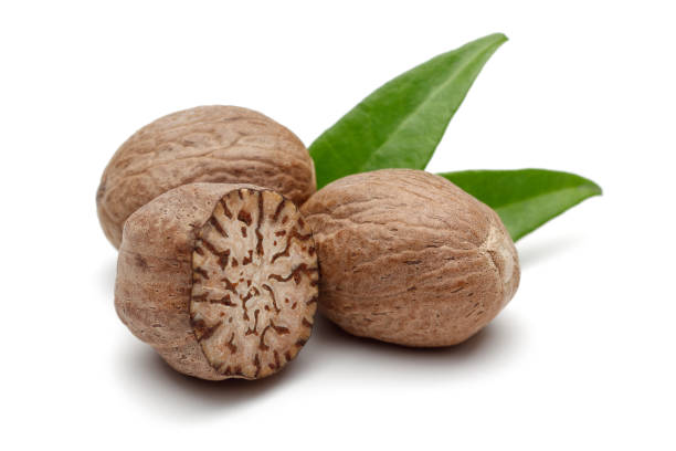 Whole and half nutmeg with leaves isolated