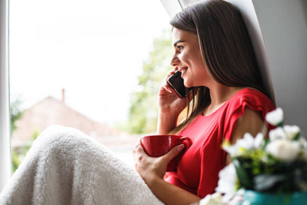 istock Happy woman having tea and talking on cell phone while relaxing at home 1162753929