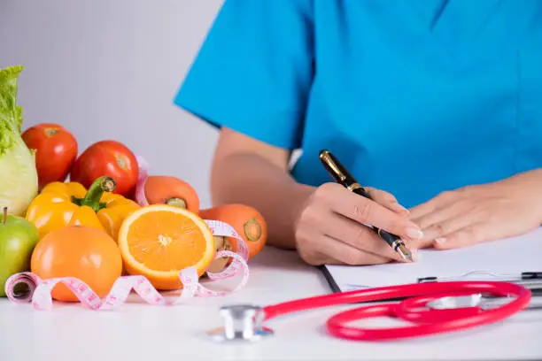 Photo of Healthy lifestyle, food and nutrition concept. Close up of fresh vegetables and fruits with stethoscope lying on doctor's desk.
