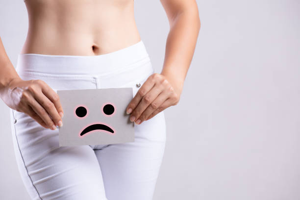 papier de fixation de jeune femme de plan rapproché avec le visage souriant triste ou malheureux près de son abdomen inférieur d'entrejambe. problèmes médicaux ou gynécologiques, concept de soins de santé. - thrush yeast fungus illness photos et images de collection