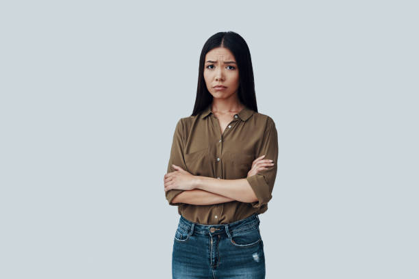 istock Feeling sad. Frustrated young Asian woman making a face while standing against grey background 1162759409
