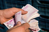 Close-up shot of senior man counting large group of Turkish Lira Banknotes