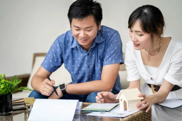 Photo of Couple consult and studying contract agreement, reading terms and conditions attentively before signing, considering loan contract buy new house.